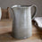 Gray ceramic pitcher on a wooden surface with a neutral background