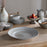 Set of Valinha grey ceramic plates and bowls on a wooden table with a neutral background
